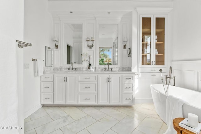 bathroom with vanity, ornamental molding, and a tub to relax in