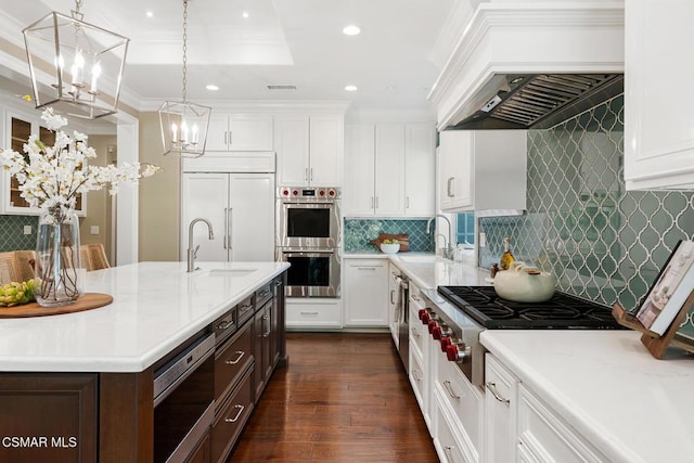 kitchen with custom exhaust hood, white cabinetry, crown molding, pendant lighting, and stainless steel appliances