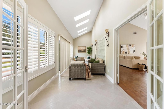 living area featuring french doors, lofted ceiling with skylight, and light tile patterned floors