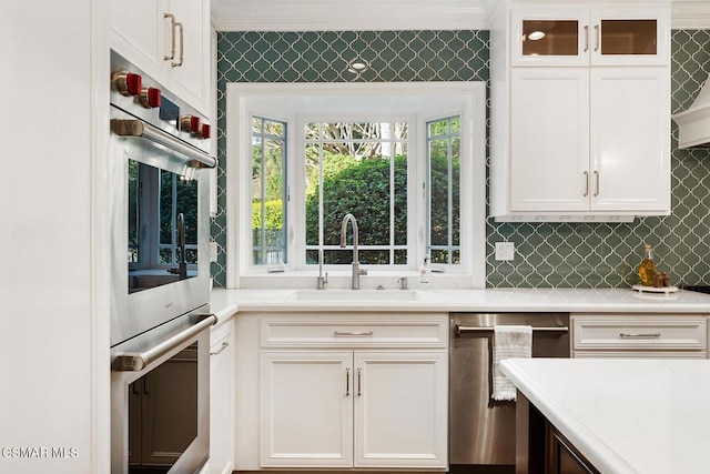 kitchen with sink, white cabinetry, double wall oven, decorative backsplash, and stainless steel dishwasher