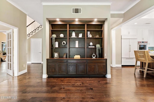 bar featuring crown molding, paneled built in fridge, dark hardwood / wood-style floors, and stainless steel oven