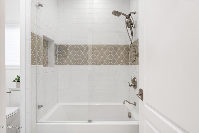 bathroom with tiled shower / bath combo and toilet