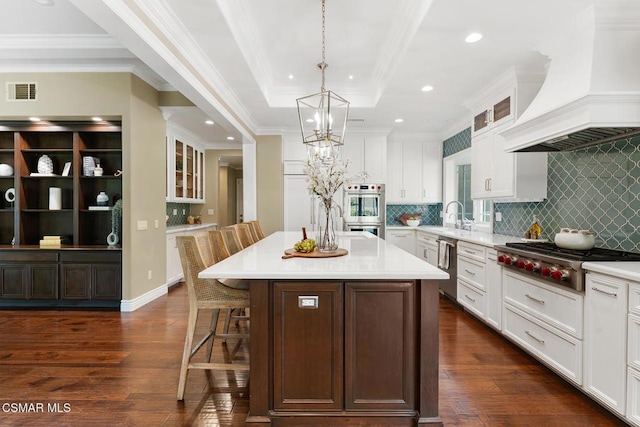 kitchen with a breakfast bar, pendant lighting, custom exhaust hood, a center island, and stainless steel appliances