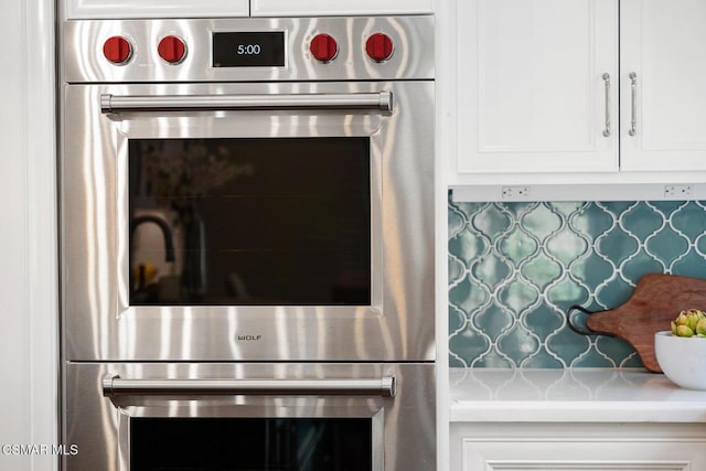 details featuring double wall oven, decorative backsplash, and white cabinets