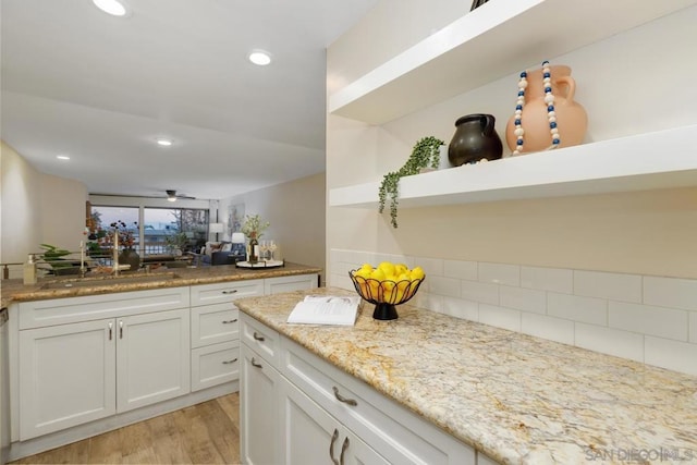 kitchen with light hardwood / wood-style flooring, dishwasher, ceiling fan, light stone countertops, and white cabinets