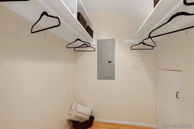 spacious closet with lofted ceiling, electric panel, and light hardwood / wood-style floors