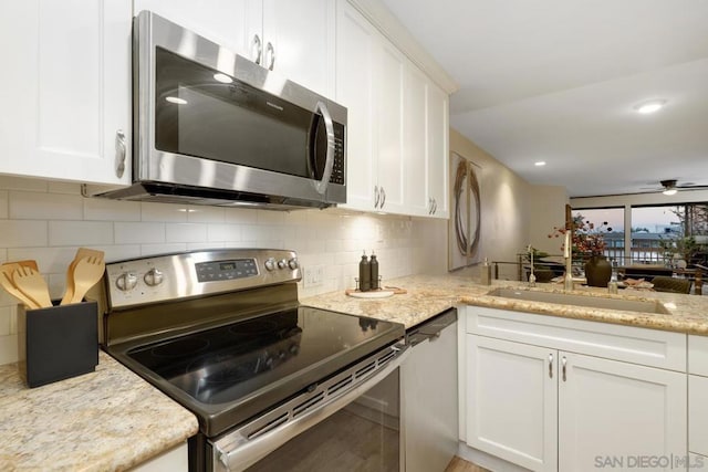 kitchen featuring stainless steel appliances, white cabinetry, sink, and light stone counters