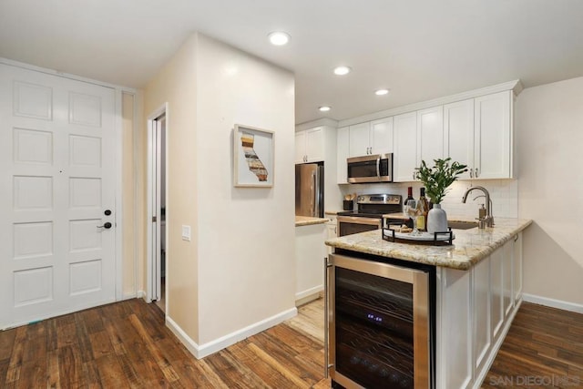 kitchen featuring white cabinetry, appliances with stainless steel finishes, wine cooler, and light stone counters