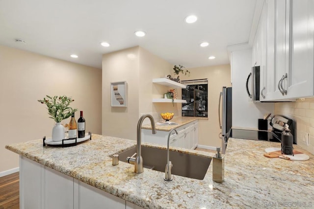 kitchen with light stone countertops, decorative backsplash, stainless steel appliances, and white cabinets