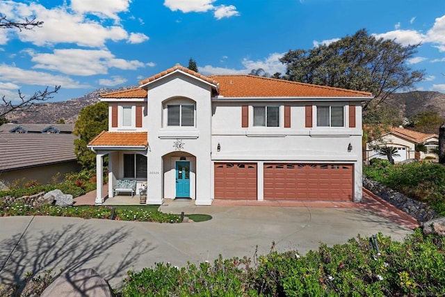 mediterranean / spanish home with a garage, a mountain view, and covered porch