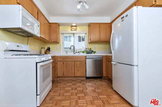 kitchen with sink, white appliances, and light parquet flooring