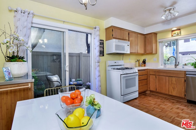 kitchen with sink, white appliances, and dark parquet flooring