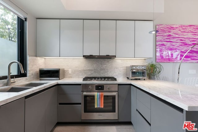 kitchen with gray cabinets, light stone countertops, and appliances with stainless steel finishes