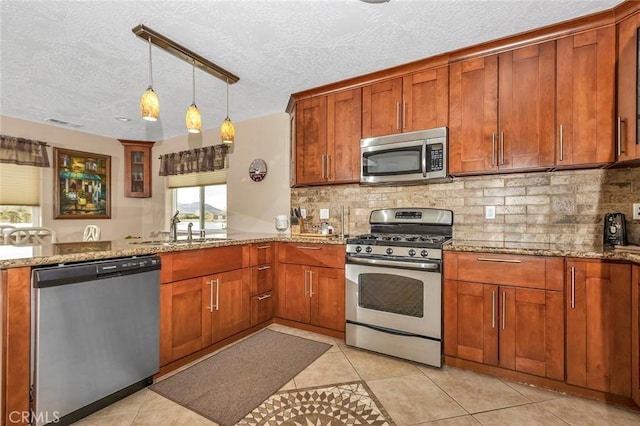 kitchen featuring hanging light fixtures, stainless steel appliances, light stone countertops, light tile patterned floors, and sink