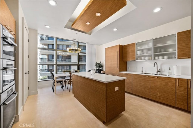 kitchen with pendant lighting, sink, a center island, a notable chandelier, and a tray ceiling