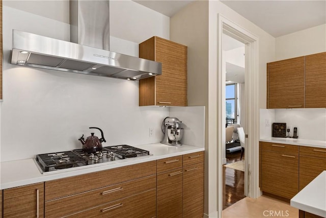 kitchen featuring stainless steel gas cooktop, wall chimney range hood, and decorative backsplash