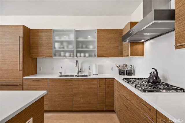 kitchen with stainless steel gas cooktop, sink, and wall chimney range hood