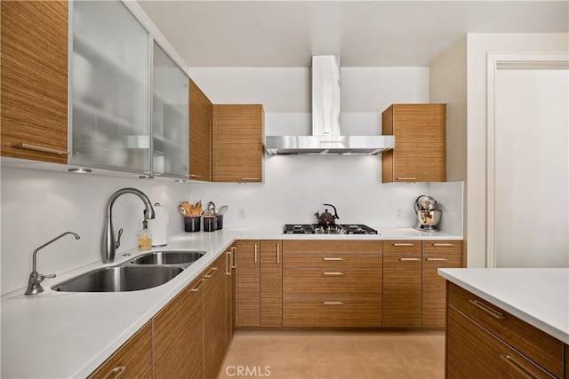 kitchen featuring light tile patterned flooring, wall chimney exhaust hood, sink, gas stovetop, and backsplash