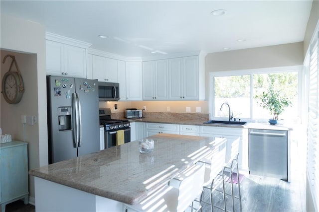 kitchen featuring white cabinetry, appliances with stainless steel finishes, sink, and a kitchen island