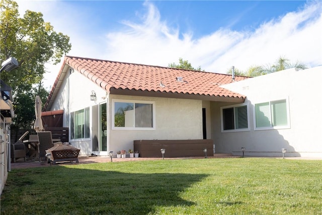 rear view of property with a fire pit and a lawn