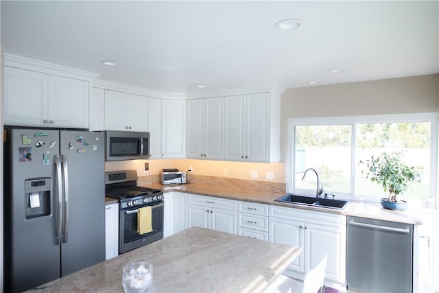 kitchen featuring white cabinetry, stainless steel appliances, sink, and light stone counters