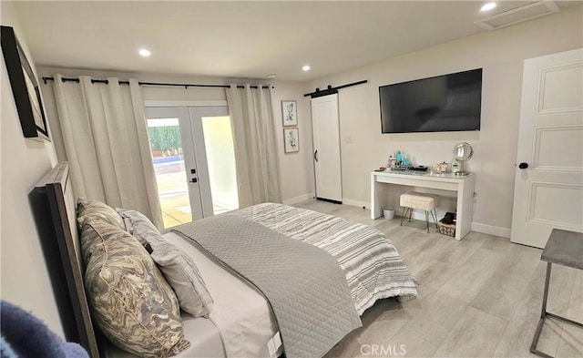 bedroom featuring french doors, a barn door, light hardwood / wood-style floors, and access to exterior