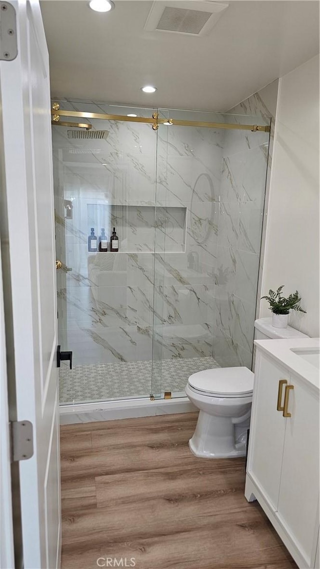 bathroom with walk in shower, wood-type flooring, toilet, and vanity