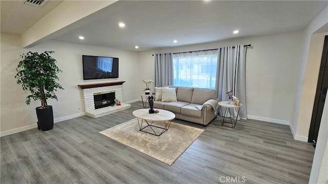 living room with a brick fireplace and light wood-type flooring