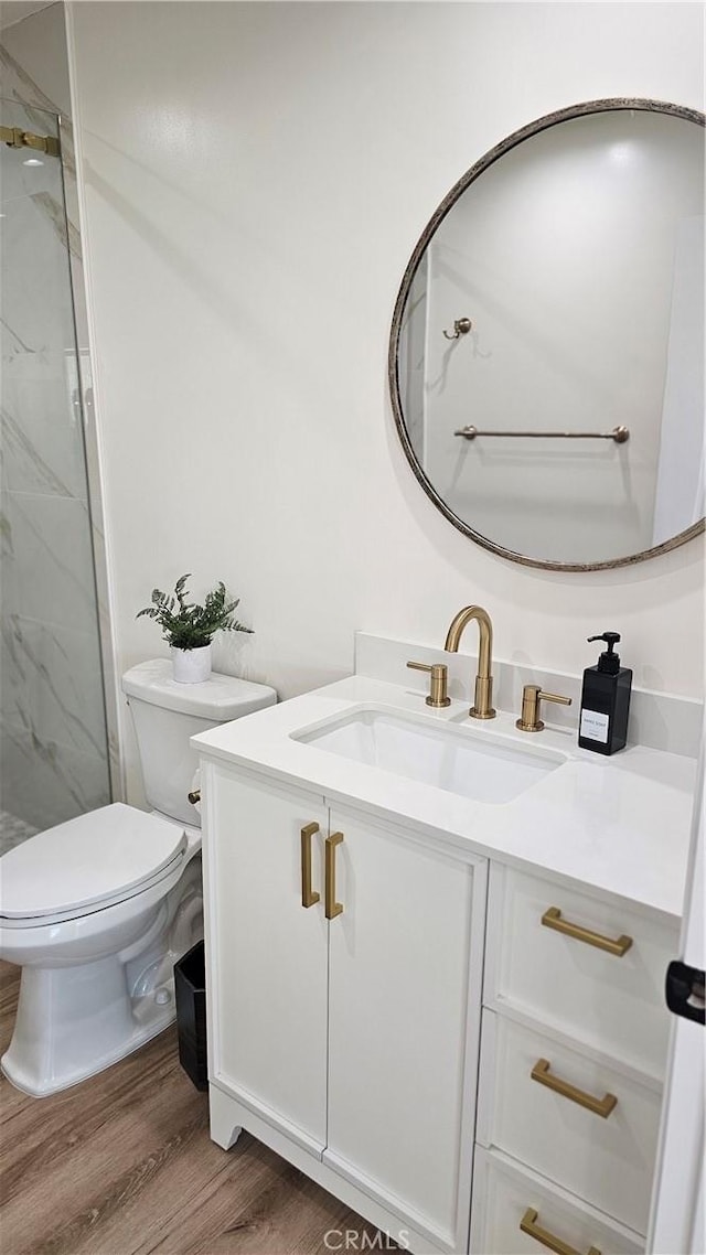 bathroom with vanity, hardwood / wood-style flooring, toilet, and a tile shower