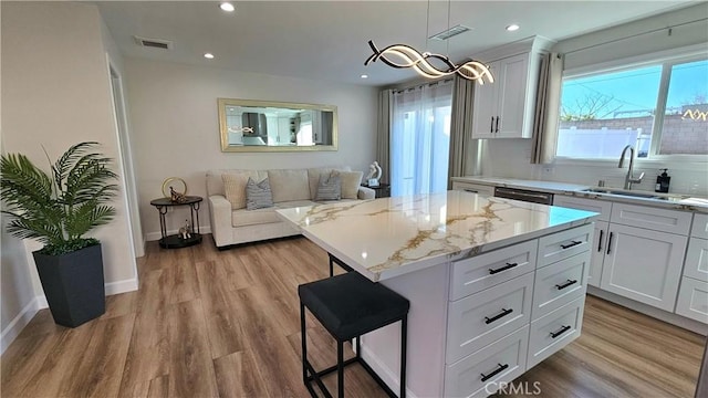 kitchen featuring a kitchen island, sink, and white cabinets