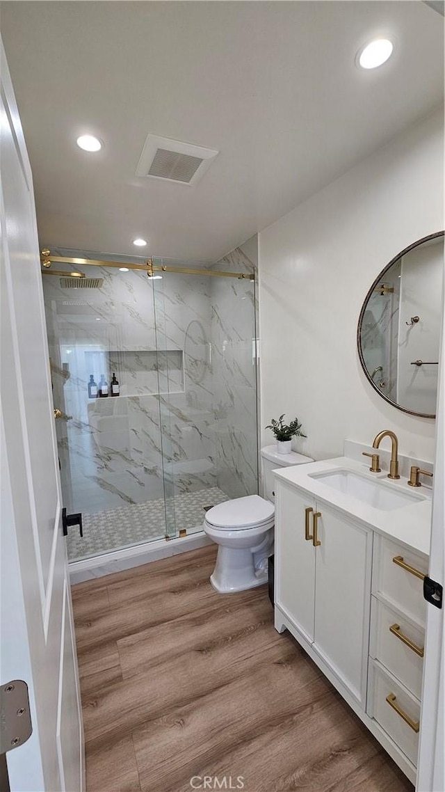 bathroom featuring hardwood / wood-style flooring, vanity, a shower with door, and toilet