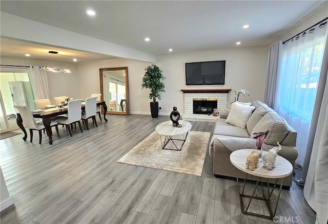 living room with a brick fireplace and light wood-type flooring