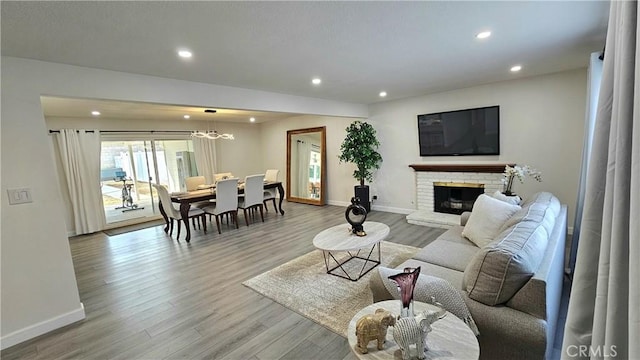 living room with a brick fireplace and light wood-type flooring