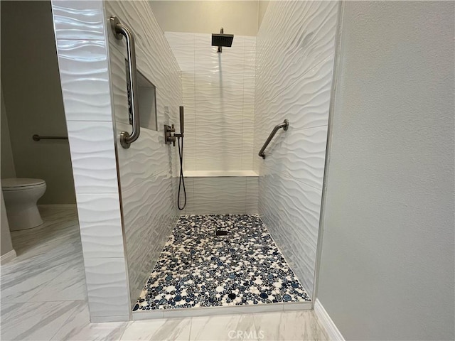 bathroom with marble finish floor, tiled shower, and toilet