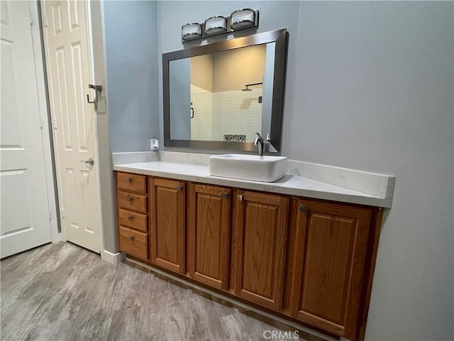 full bath featuring a shower, wood finished floors, and vanity