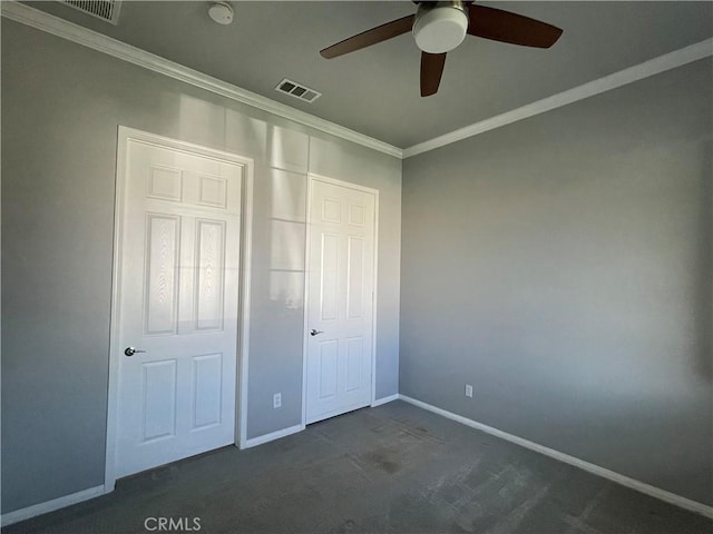 unfurnished bedroom featuring baseboards, dark colored carpet, visible vents, and crown molding