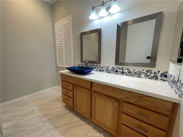 bathroom with marble finish floor, vanity, and baseboards