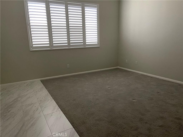 empty room featuring marble finish floor and baseboards