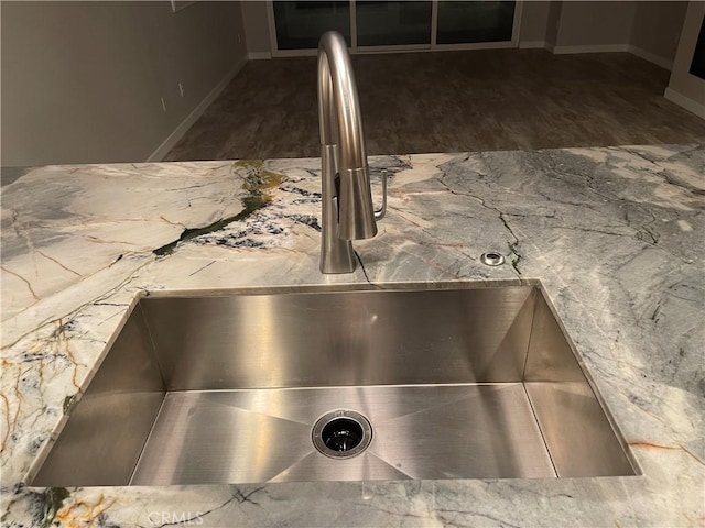 room details with dark wood-style flooring, a sink, and baseboards