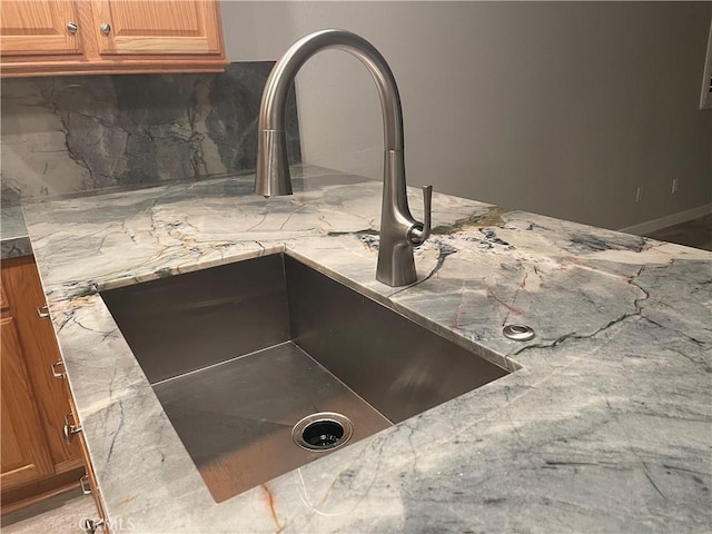 details with brown cabinetry, backsplash, and a sink