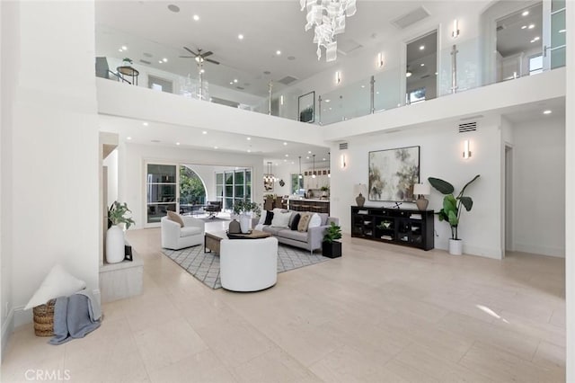 living room featuring light tile patterned floors, ceiling fan with notable chandelier, and a high ceiling