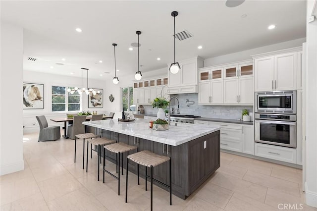 kitchen featuring a large island, white cabinetry, decorative light fixtures, and appliances with stainless steel finishes