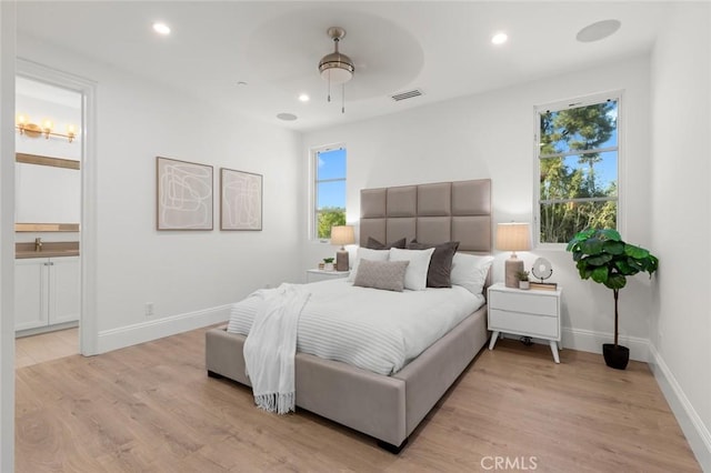 bedroom with sink, ensuite bath, light hardwood / wood-style flooring, and ceiling fan