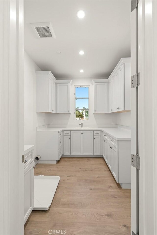 kitchen featuring white cabinetry, sink, and light hardwood / wood-style floors