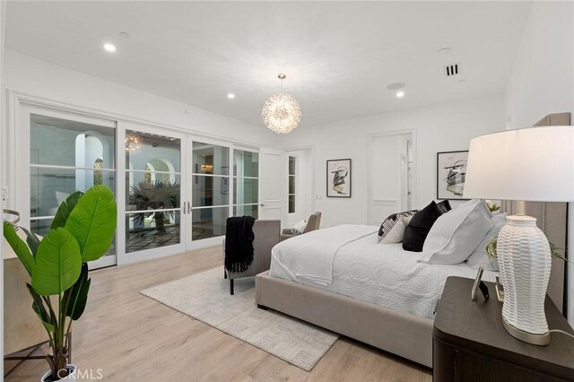 bedroom featuring an inviting chandelier, access to exterior, light hardwood / wood-style flooring, and french doors