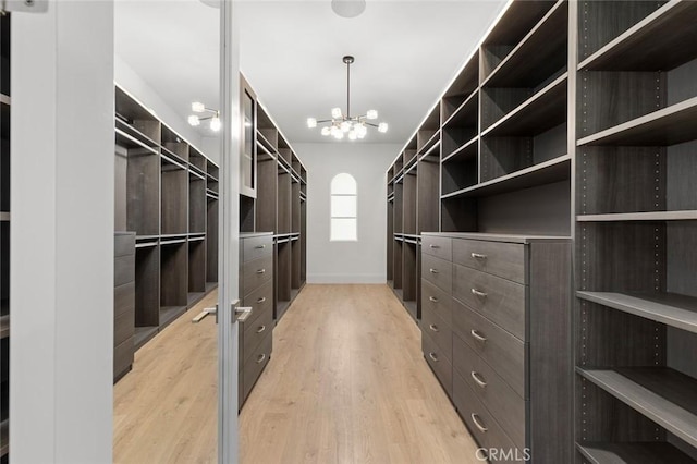 walk in closet with a chandelier and light hardwood / wood-style floors