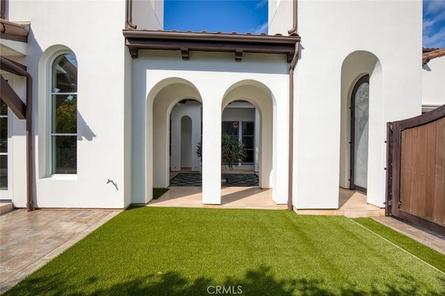 back of property with a lawn and a patio