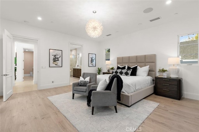 bedroom with an inviting chandelier, ensuite bath, and light wood-type flooring