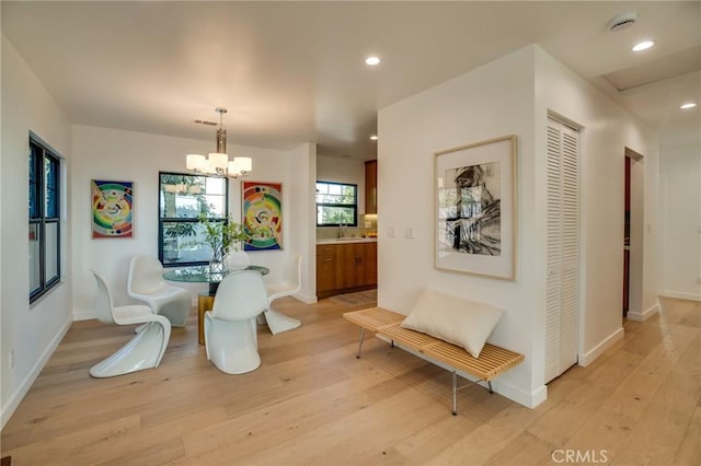 dining space with a notable chandelier, sink, and light wood-type flooring