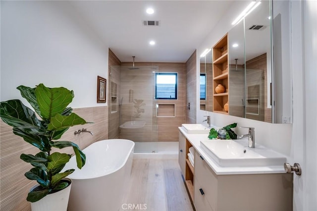 bathroom featuring hardwood / wood-style flooring, vanity, plus walk in shower, and tile walls